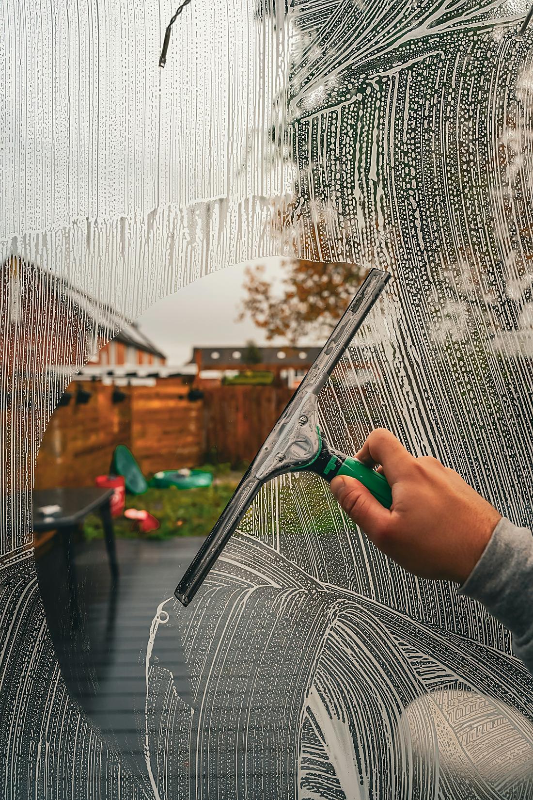 Haynes window cleaner using a squeegee on a soapy window