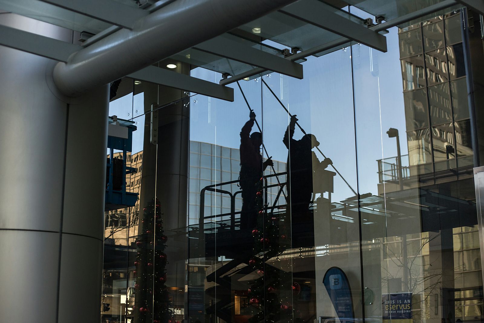 Window cleaners reflected in a large commercial glass facade