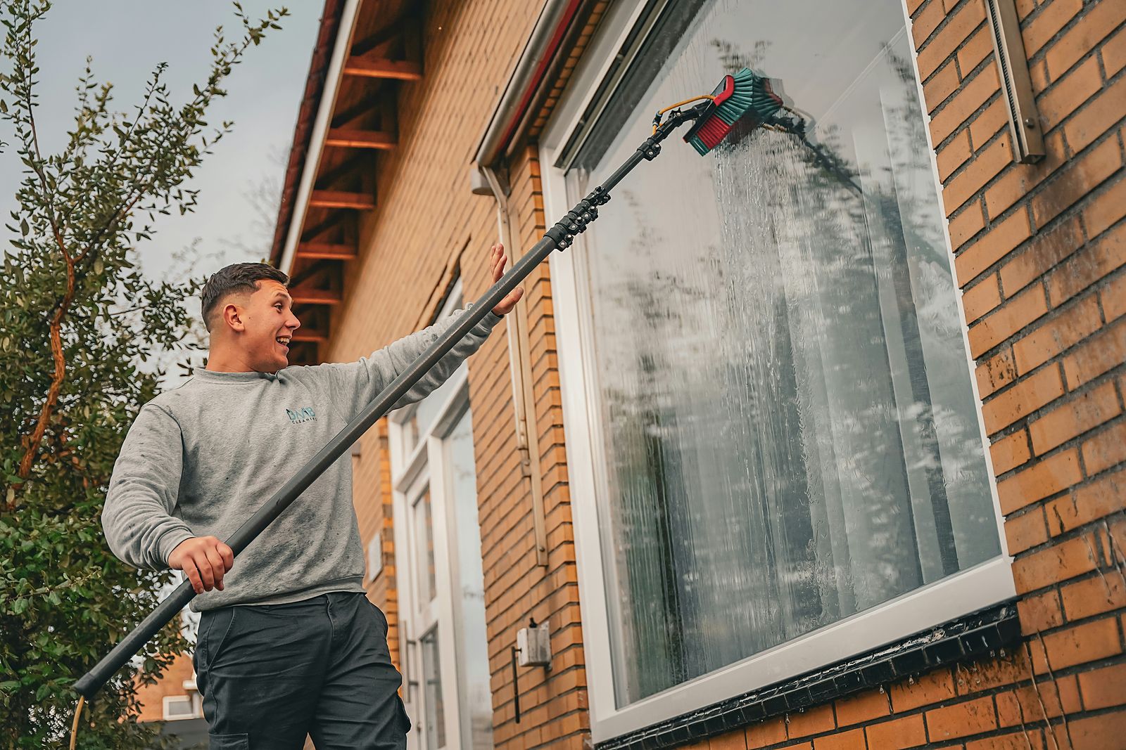 Window cleaner using a water-fed pole on a brick building