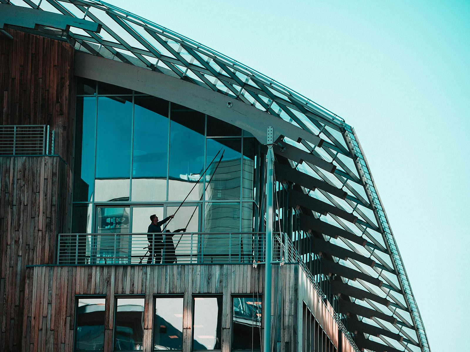 Modern glass building with a cleaner working on a balcony