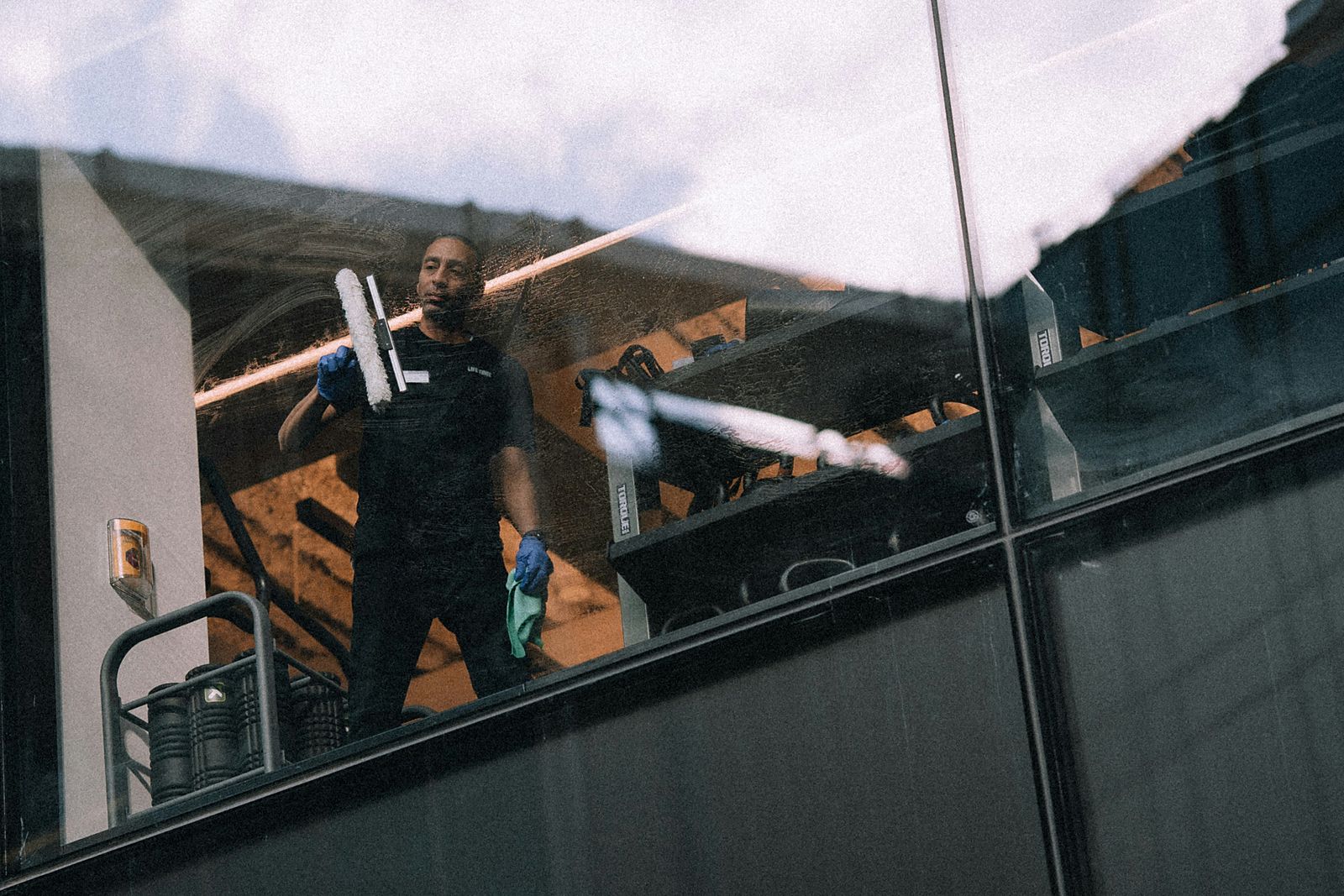 Rope-access window cleaner on a dark building facade
