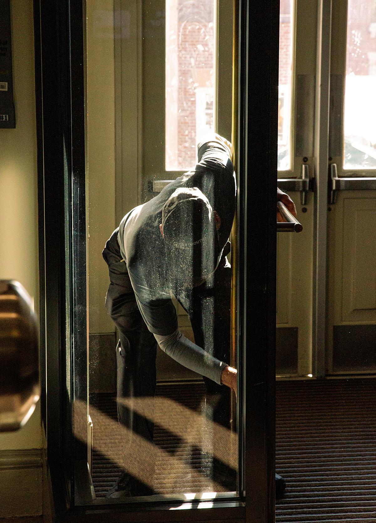 Rope-access cleaner descending past a glass frontage